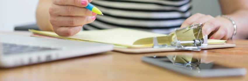 close-up-das-maos-de-escrita-em-uma-prancheta